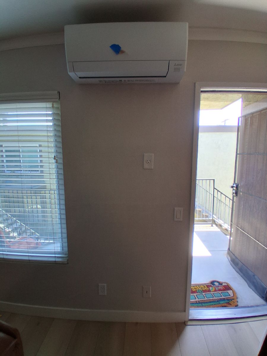 Finished interior wall below a wall-mounted mini-split after documented AWC drywall and paint work